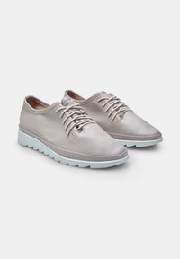 Sneakers in pelle rosa chiaro con una finitura liscia, punta tonda, design con lacci e suola in gomma bianca con un motivo testurizzato.