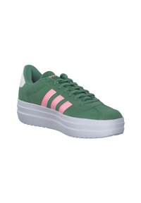 Zelene nubuk tenisice s roza tri pruge, okrugli vrh, podstavljena ojačanja, i bijela platforma. Ima teksturirane detalje po cijeloj površini.