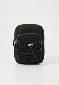 Sort rygsæk med tekstureret stof, der har en forreste netlomme, lynlås og mærke-logo. Kompakt rektangulær form.