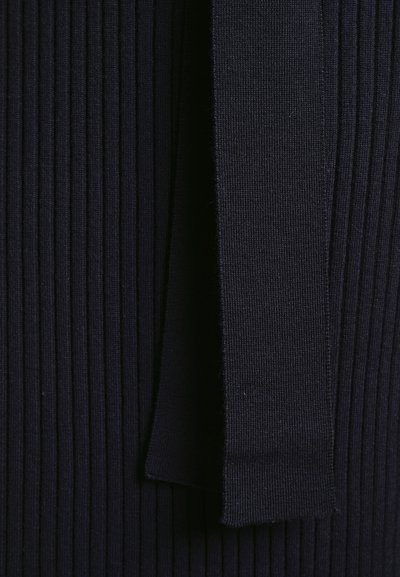 Mørkeblå ribbet stof med en glat tekstur, en bred lodret stripe og et hængende bånddetalje på højre side.