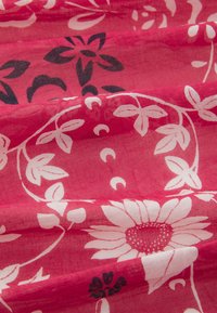 Rosa blommönstrad tyg med vita och svarta mönster, med stora blommor och intrikata bladdesigns, slät textur med en lätt och luftig kvalitet.