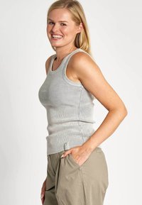 Graues geripptes Tanktop mit figurbetontem Design und breiten Trägern, kombiniert mit lockeren beigen Hosen mit einem Knopfbeutel.