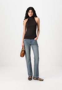 Top halter negru, blugi drepți de culoare albastru deschis și pantofi cu model leopard. Poșetă maro cu mâner scurt, din material din piele texturată.