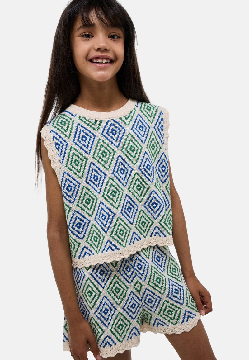 Ensemble en tricot à deux pièces avec des motifs de diamants verts et bleus sur un fond crème, avec des bords festonnés sur le haut et le short.