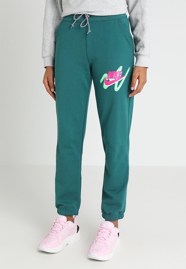 Teal sweatpants har en elastisk midja med dragsko, elastiska muddar och en rosa Nike-logotyp med gröna accenter på vänster lår.