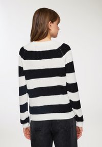 Sweter dzianinowy z poziomymi czarno-białymi paskami, okrągłym dekoltem i ściągaczami. Teksturowany materiał i luźny krój.