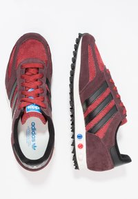 Bordeauxmocka och mesh sportskor med svarta ränder, vit sula och färgglada hål. Har texturerad tyg och vadderad krage.