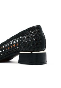 Scarpa piatta nera intrecciata con tacco quadrato. Presenta una tomaia testurizzata e intrecciata con dettagli in pelle liscia. Design minimalista con una silhouette discreta.