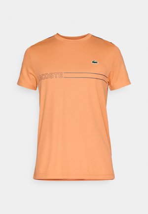 Korte mouwen, ronde hals t-shirt in oranje, met een horizontale streep en de tekst "LACOSTE" in een donkere kleur gedrukt, met een klein groen krokodil logo.