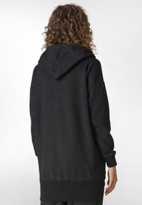 Sudadera con capucha negra de tela texturizada, con puños y dobladillo acanalados. Presenta una capucha amplia y un corte relajado, adecuada para el uso informal.