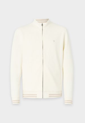 Chaqueta cremóna con cremallera hecha de un tejido suave, con un cuello alto, puños acanalados con rayas beige y un pequeño logotipo en el pecho.