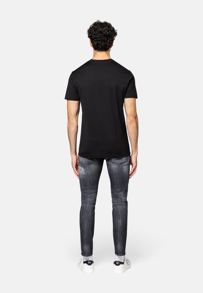 Zwarte crew-neck t-shirt, korte mouwen, gecombineerd met vervaagde grijze denim jeans. Witte sneakers met zwarte accenten. Achteraanzicht van de outfit.