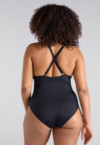 Svart baddräkt i ett stycke med en korsad ryggdesign, justerbara axelremmar och en slät yta. Inga ytterligare mönster eller detaljer.