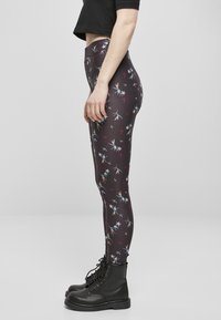 Leggings floraux noirs avec des imprimés colorés, taille haute, matière extensible, associés à des bottes de combat noires à lacets.