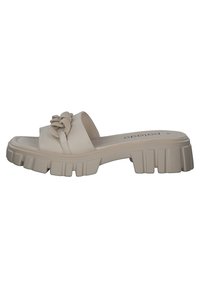 Infradito beige realizzati in materiale liscio, con un accento floreale sulla cinghia e una suola spessa e testurizzata con motivi di battistrada pronunciati.