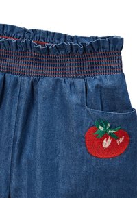 Shorts en denim avec une taille froncée, ornés de coutures rouges et d'un motif de tomate brodé sur la poche avant.