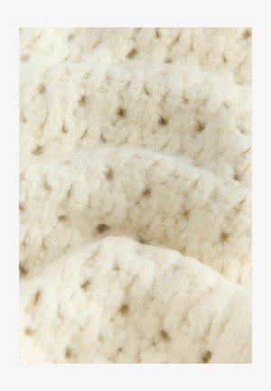 Pletená tkanina krémovej farby s textúrovaným vzorom, obsahujúca vystúpené bodky v svetlohnedej farbe. Mäkkučká, hrubá priadza s nadýchaným vzhľadom.