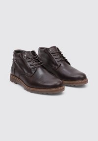 Botas de tobillo de cuero marrón con puntas redondeadas, diseño con cordones y suelas de goma tostada. Marca sutil y superficies de cuero texturizadas.