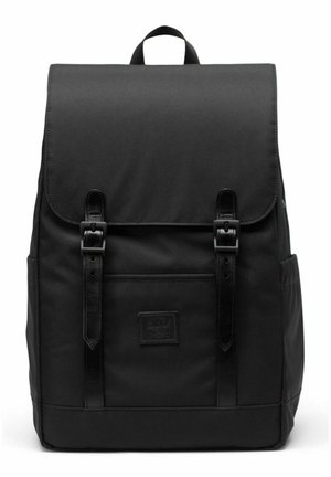 Sac à dos en tissu noir avec rabat fermé par deux sangles en cuir et boucles, poche avant et poignée supérieure.