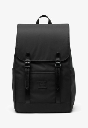 Sac à dos en tissu noir avec rabat fermé par deux sangles en cuir et boucles, poche avant et poignée supérieure.