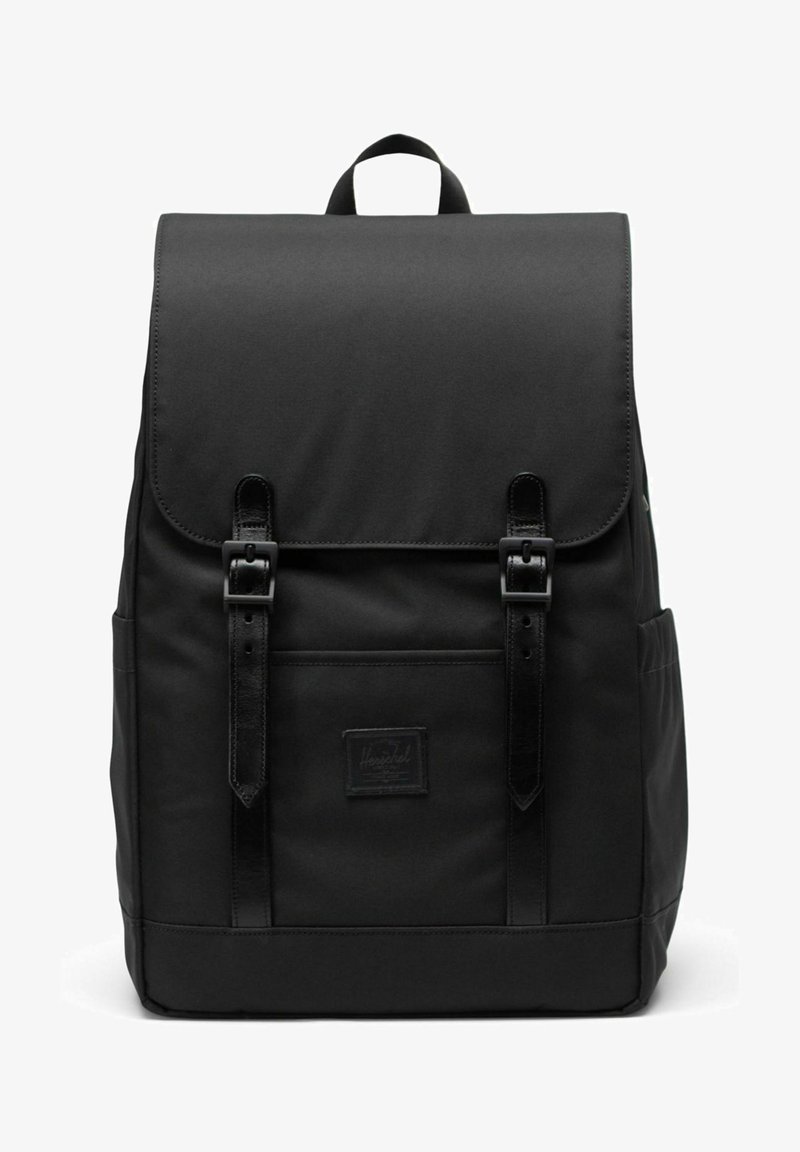 Sac à dos en tissu noir avec rabat fermé par deux sangles en cuir et boucles, poche avant et poignée supérieure.