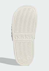 Adidas shoe sole in off-white rubber with a textured herringbone pattern, featuring embossed branding and size indicator on the side.