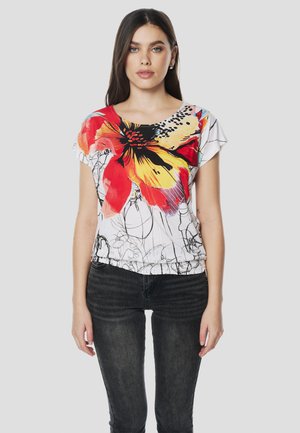 Maglietta a maniche corte floreale con un grande motivo a fiore rosso e giallo su base bianca, con disegni a linee nere e orlo arricciato.