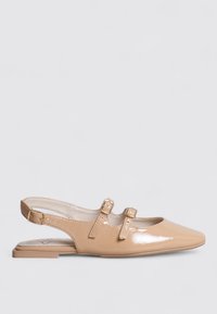 Chaussures slingback en cuir verni beige avec deux sangles à boucle ajustables, bout pointu et semelle plate. Texture lisse avec finition brillante.