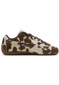 Sneakers a profilo basso con un motivo a macchie di mucca in suede marrone e beige. Presentano una suola in gomma marrone e lacci marroni.