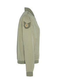 Veste bomber vert clair avec poignets et col côtelés, dotée d'un patch style militaire avec une étoile dorée sur la manche supérieure.