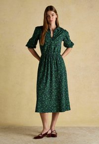 Roheline lilleline kleit, millel on krae, elastne vöökoht ja lühikesed puffvarrukad. Kombineeritud marooni värvi seljatoe kingadega, millel on plokkkontsad.