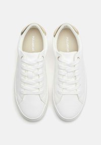 Fehér, fűzős tornacipők sima vászon felsőrésszel, világosbarna sarokdísszel és bézs, márkás talpbetéttel.