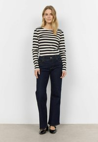 Maglietta a maniche lunghe a righe bianche e nere abbinata a jeans a zampa d'elefante blu scuro. L'outfit presenta un design classico con una parte superiore aderente e una parte inferiore morbida.