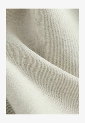 Tessuto beige chiaro dalla texture con un sottile motivo a trama, con superfici lisce e leggermente opache, che mostrano morbide pieghe.
