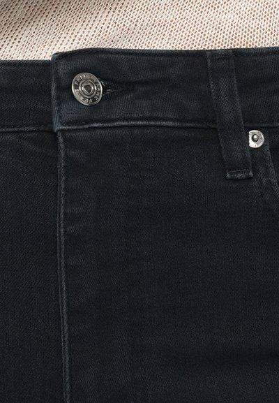 Jeans de ganga escura com fecho frontal de botões, detalhes costurados e textura suave. Sem padrões visíveis; design minimalista.