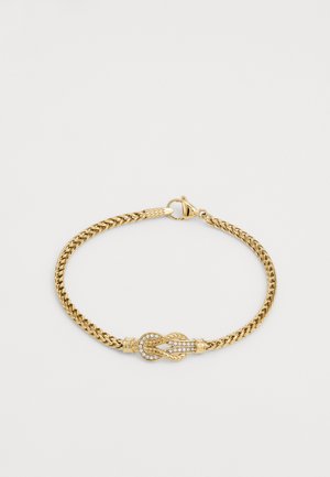 Goldfarbener Armreifen mit gedrehter Kettenoptik, der ein zentrales Knotendesign aufweist, das mit klaren Strasssteinen verziert ist, um zusätzliche Details zu bieten.