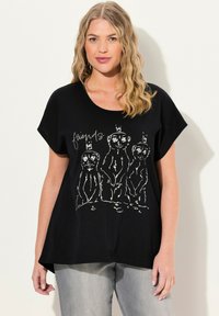 Camiseta negra de manga corta con un gráfico blanco de tres suricatas con coronas y la palabra "amigos" arriba, hecha de un material suave.