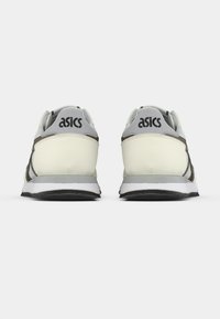 ASICS spordijalatsid kreemi ja halli värvitoonis. Omavad siledat sünteetilist pealispinda, pehmendatud kaelust, musta kummist tallat ja silmapaistvat brändimist kandadel.