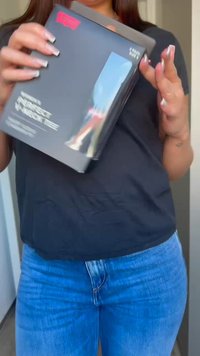 Ambalaj rectangular negru cu un fereastră transparentă, având text alb îndrăzneț. Produsul este ținut într-o mână, evidențiind designul său elegant.
