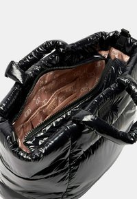 Borsa nera gonfiabile con un esterno lucido e trapuntato e due manici spessi. L'interno presenta un rivestimento rosa morbido e una tasca con zip.