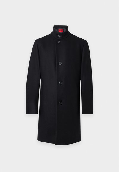 Manteau noir longueur genou avec col montant et cinq boutons devant, présenté sur un fond clair uni.