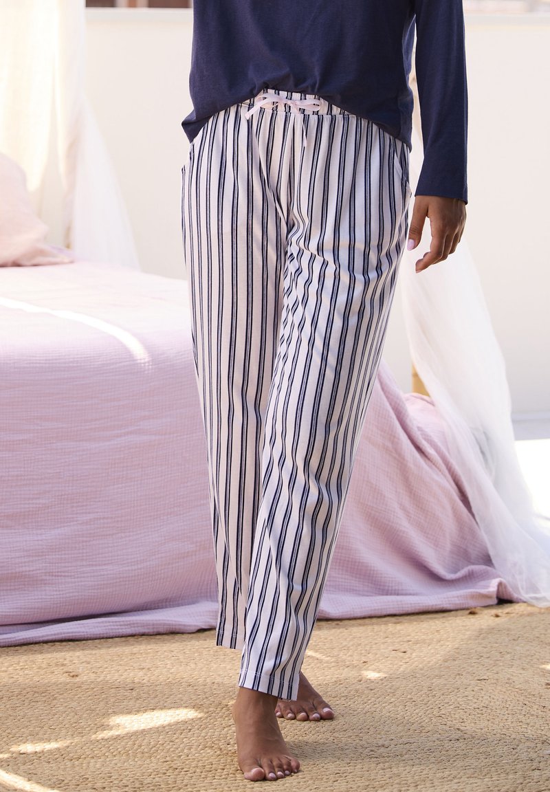 Striped pajama pants in white and navy, featuring a drawstring waist and a relaxed fit, made of lightweight fabric for comfort.