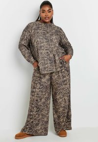 Lågmäld leopardmönstrad lounge-set som inkluderar en löst sittande långärmad topp och vida byxor i beige och bruna nyanser, tillverkad av mjukt tyg.