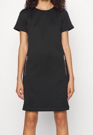 Black dress with short sleeves, ribbed neckline, and zippered side pockets. Made from smooth fabric, featuring contrasting side accents.