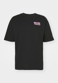 Camiseta de algodón negra de manga corta y cuello redondo. Presenta un gráfico rosa de "NEW YORK YANKEES" en la parte superior izquierda.