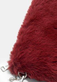 Bordo umetni krzneni žep z mehko teksturo, ki vključuje srebrno kovinsko zaponko in obroček za ključe za enostavno prenašanje.