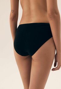 Czarne majtki typu high-waisted o gładkiej, matowej teksturze. Projekt zawiera zaokrąglone cięcie, podkreślające kształt ciała bez wzorów.