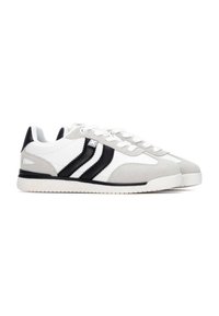 Zapatillas blancas y grises con rayas negras, hechas de cuero y ante, que cuentan con una suela texturizada y un cierre de cordones en la parte delantera.