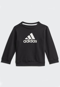 Czarna bluza z gładkiego materiału, z długimi rękawami, okrągłym dekoltem, zatrzaskami na ramieniu oraz białym logo Adidas z przodu.