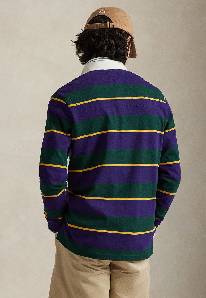 Polo à manches longues avec rayures horizontales violettes et vertes, agrémenté d'accents jaunes. Matière douce, coupe décontractée, et col classique.
